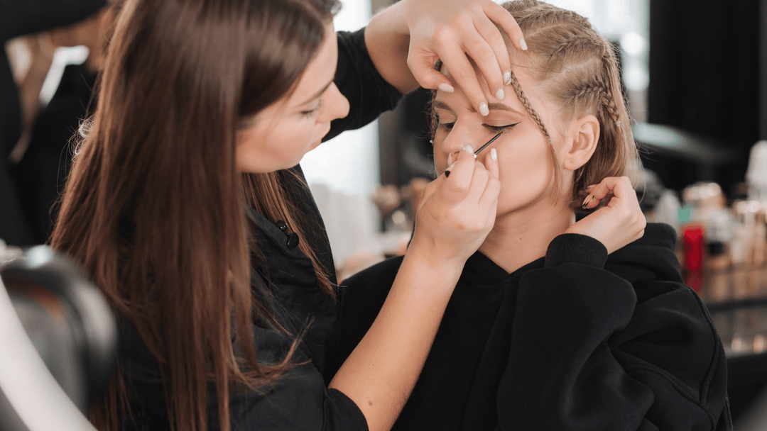 En makeup-artist applicerar försiktigt eyeliner på en modell, med fokus på precision och detaljer för att skapa en elegant och skarp look. Perfekt för den som vill ha en professionell och noggrant applicerad makeup som framhäver ögonen.